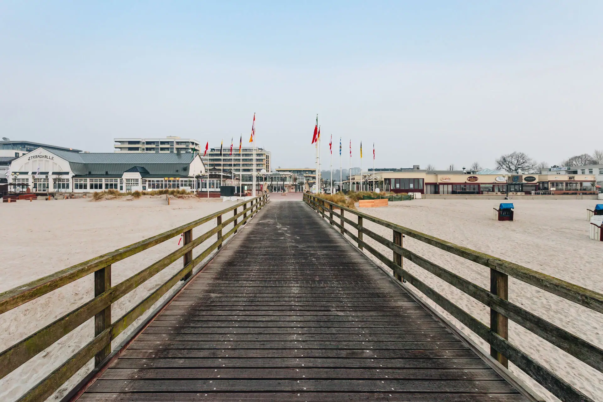 aja Grömitz Holzbrücke über einem Strand mit klarem Himmel im Hintergrund.