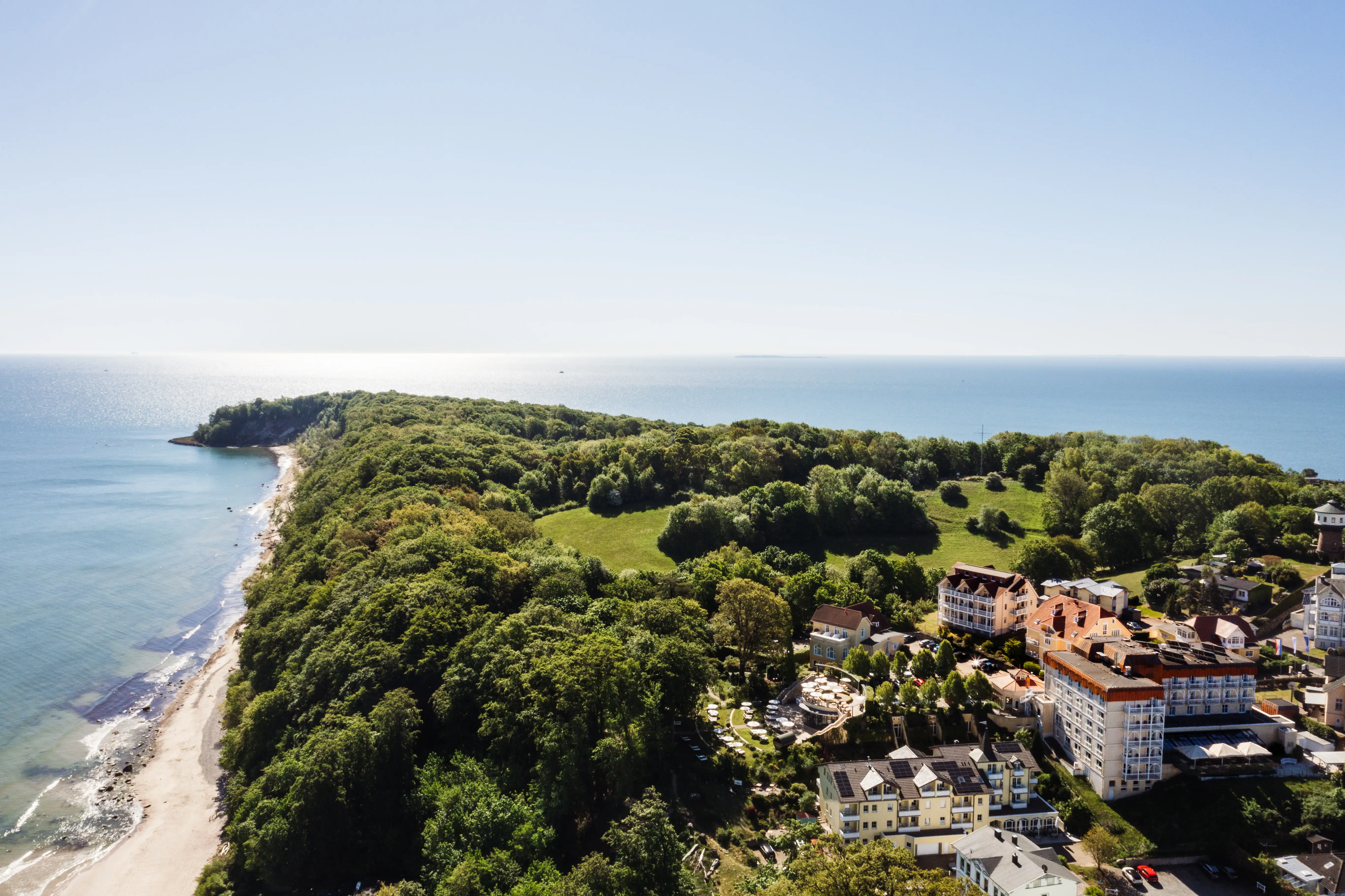 aja Nordperd & Villas Landscape with trees and buildings, coastline and sea in the background.
